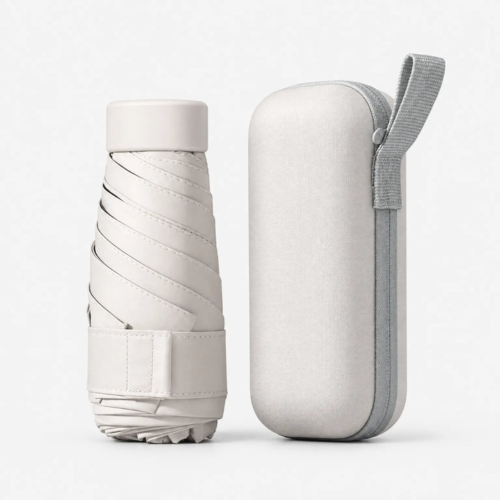 Cream folded umbrella with its cap and strap beside a matching hard zippered case with a grey wrist loop, on white. 6