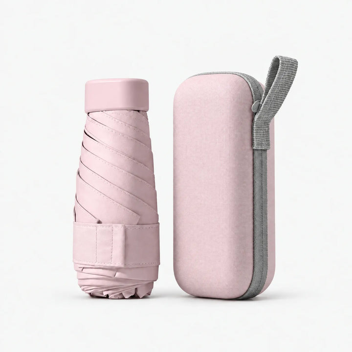 Pale pink folded umbrella with cap and strap standing next to a matching hard zippered case with a grey loop, on white. 9