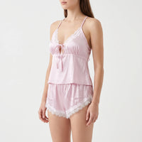 Angled front view of the pink satin pyjama set, showing the bow-tied keyhole neckline and lace-scalloped shorts. 4
