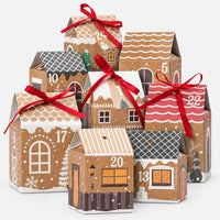The same gingerbread-style kraft boxes with numbered doors and red satin ribbons arranged as a village against a plain white background. 2