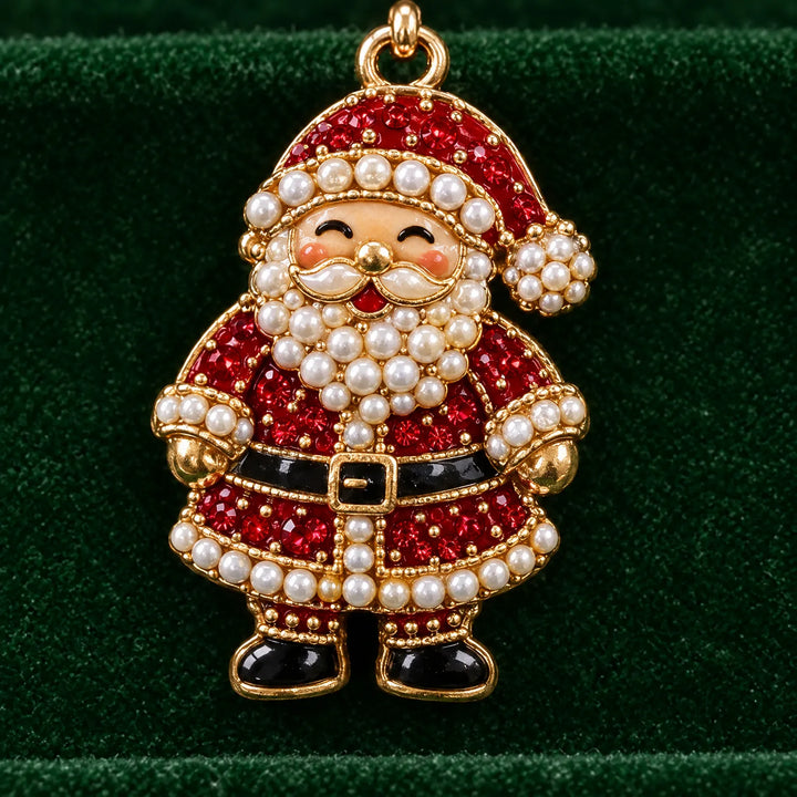 Close-up of the smiling Santa charm covered in red crystals and white pearls with gold edging, resting against green velvet. 3