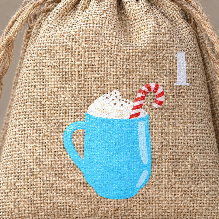 Close-up of one burlap drawstring bag showing the woven texture, jute cord and a printed blue mug with whipped cream and a candy cane. 3