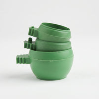 Three green plastic bowls stacked together, each with a ridged clip handle on the side, against a plain white background. 1