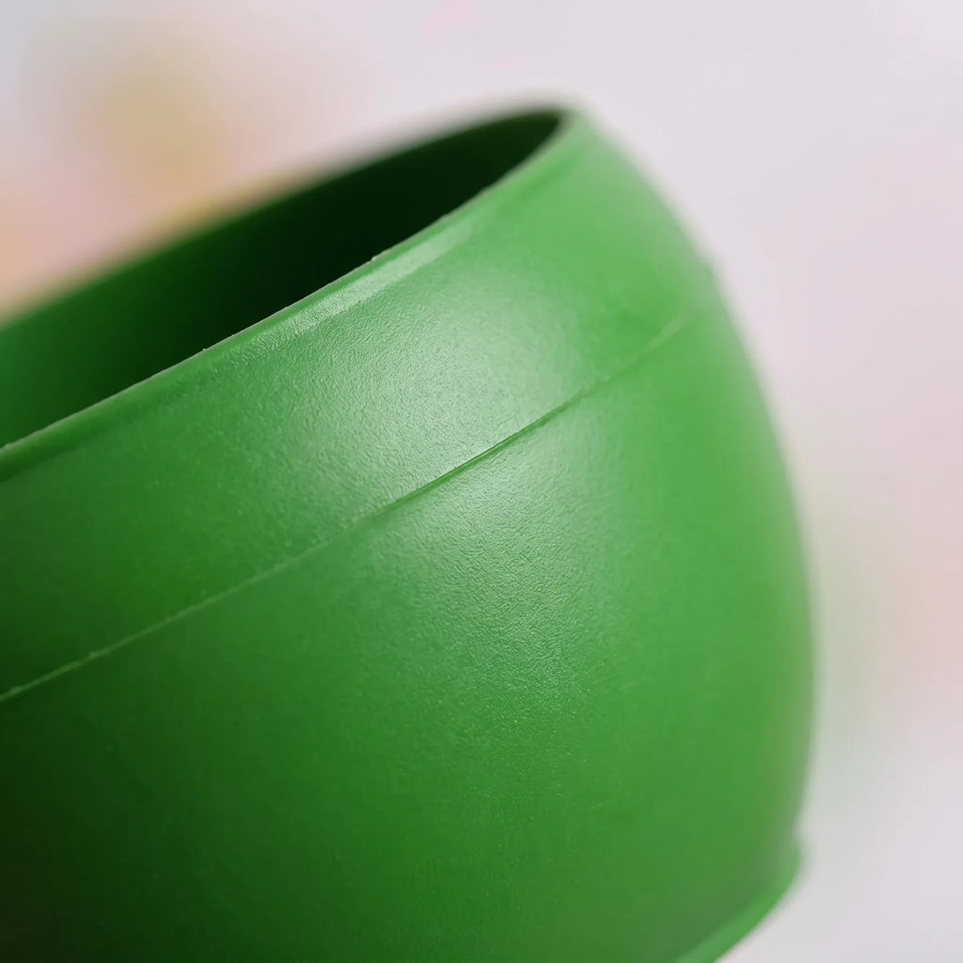 Close-up of the rim and curved side of a green plastic bowl, showing the matte surface and a moulded seam line. 3