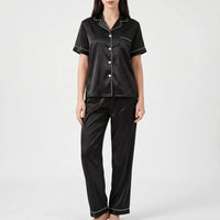 Model wearing the black satin version of the pyjama set with white piping and white buttons. 7