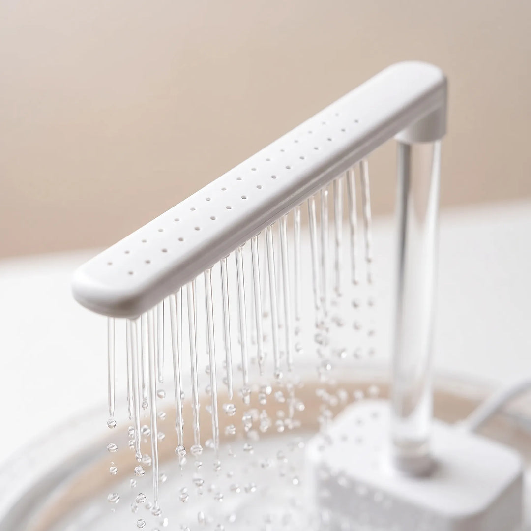 Close-up of the white shower bar with its rows of small holes and fine water streams dripping from it above the dish. 3
