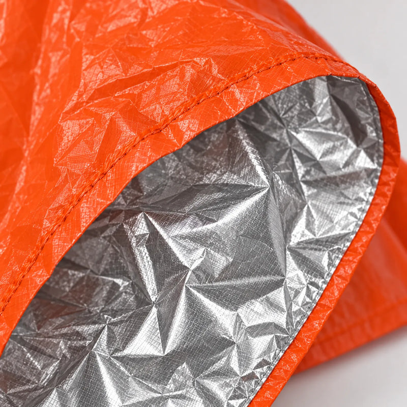 Close-up of the poncho's stitched hem, showing the crinkled orange outer surface and the reflective silver lining inside. 5