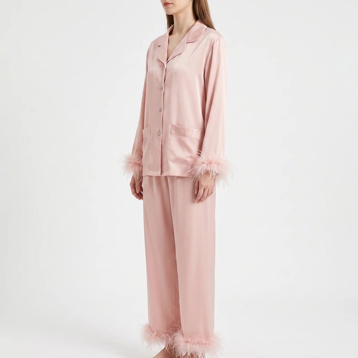 Side three-quarter view of the pink satin pyjama set on a model, showing the notched collar, patch pockets and feather trim. 4
