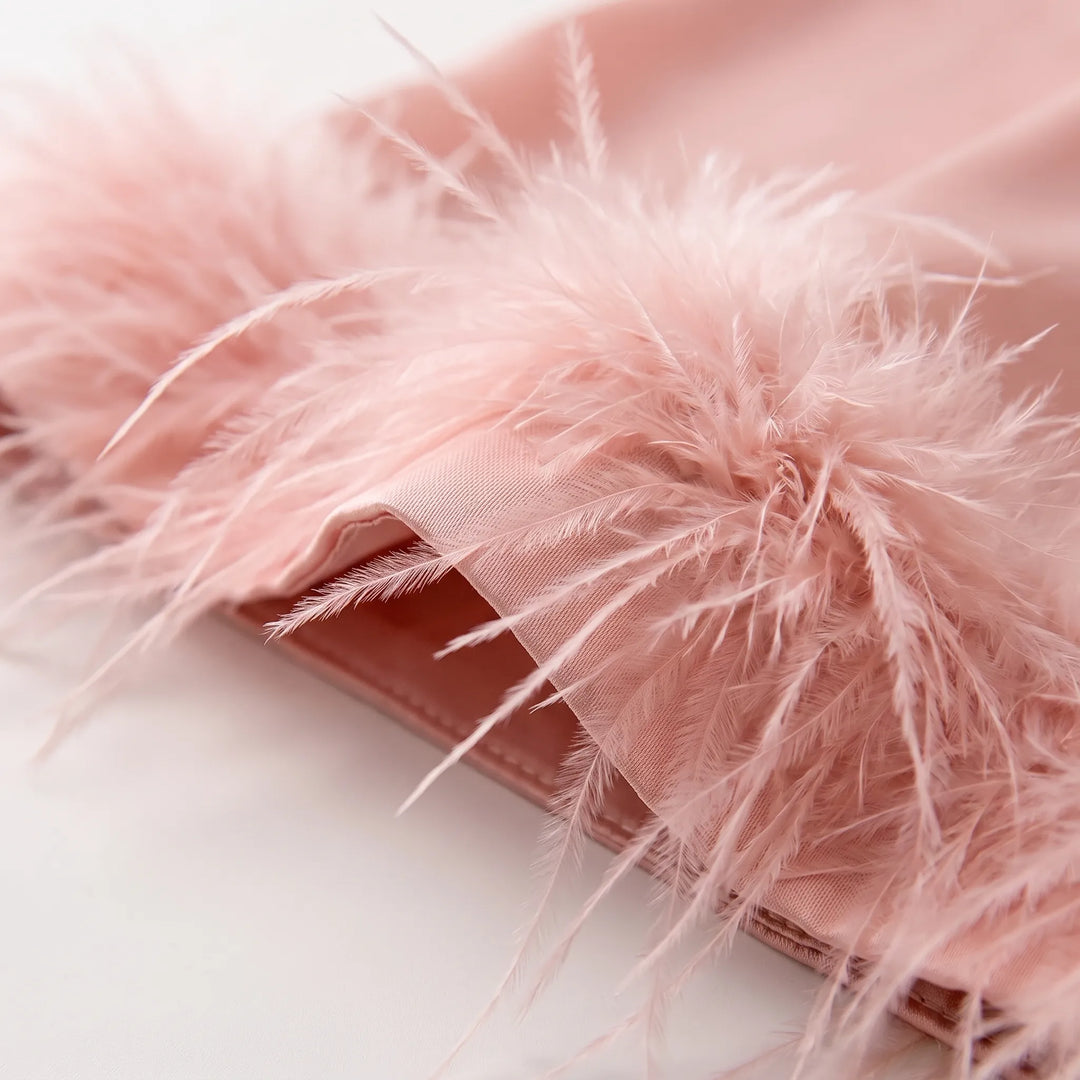 Close-up of soft pink feather trim stitched onto a satin cuff, showing the fine fluffy feathers and the fabric edge. 5