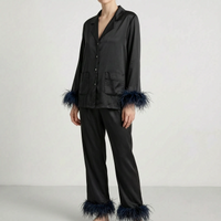 Model wearing the black satin version of the pyjama set with dark navy feather trim at the cuffs and trouser hems. 7