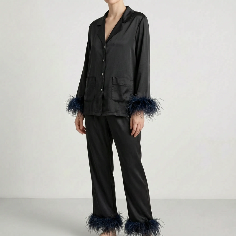 Model wearing the black satin version of the pyjama set with dark navy feather trim at the cuffs and trouser hems. 7