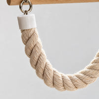 Close-up of the twisted natural rope, its white end cap and metal rings, hanging from the wooden perch. 3