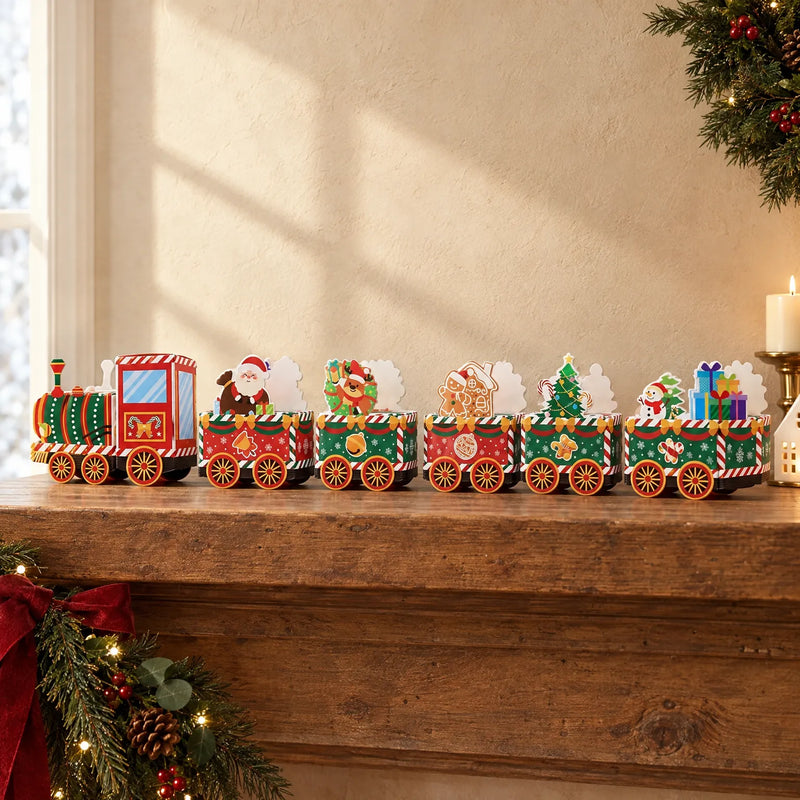 Assembled paper train with locomotive and festive wagons carrying Santa, reindeer, gingerbread, tree, snowman and gifts, displayed on a wooden mantel beside gre 1