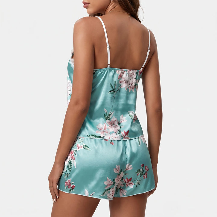 Back view of the satin set on a model, showing thin adjustable white straps, elasticated back neckline and floral print on cami and shorts. 3