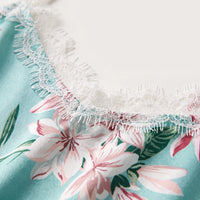 Close-up detail of the white eyelash lace trim stitched along the neckline of the aqua satin cami, with pink flowers beneath. 5