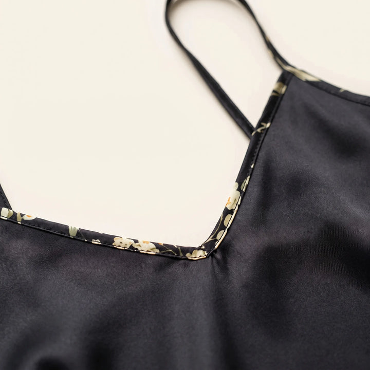 Close-up of the V-neckline of the black satin cami, showing floral-print piping edge and a thin strap. 5