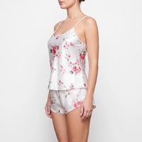 Side view of the white satin set on a model, showing a scoop neckline, thin straps and curved shorts. 4
