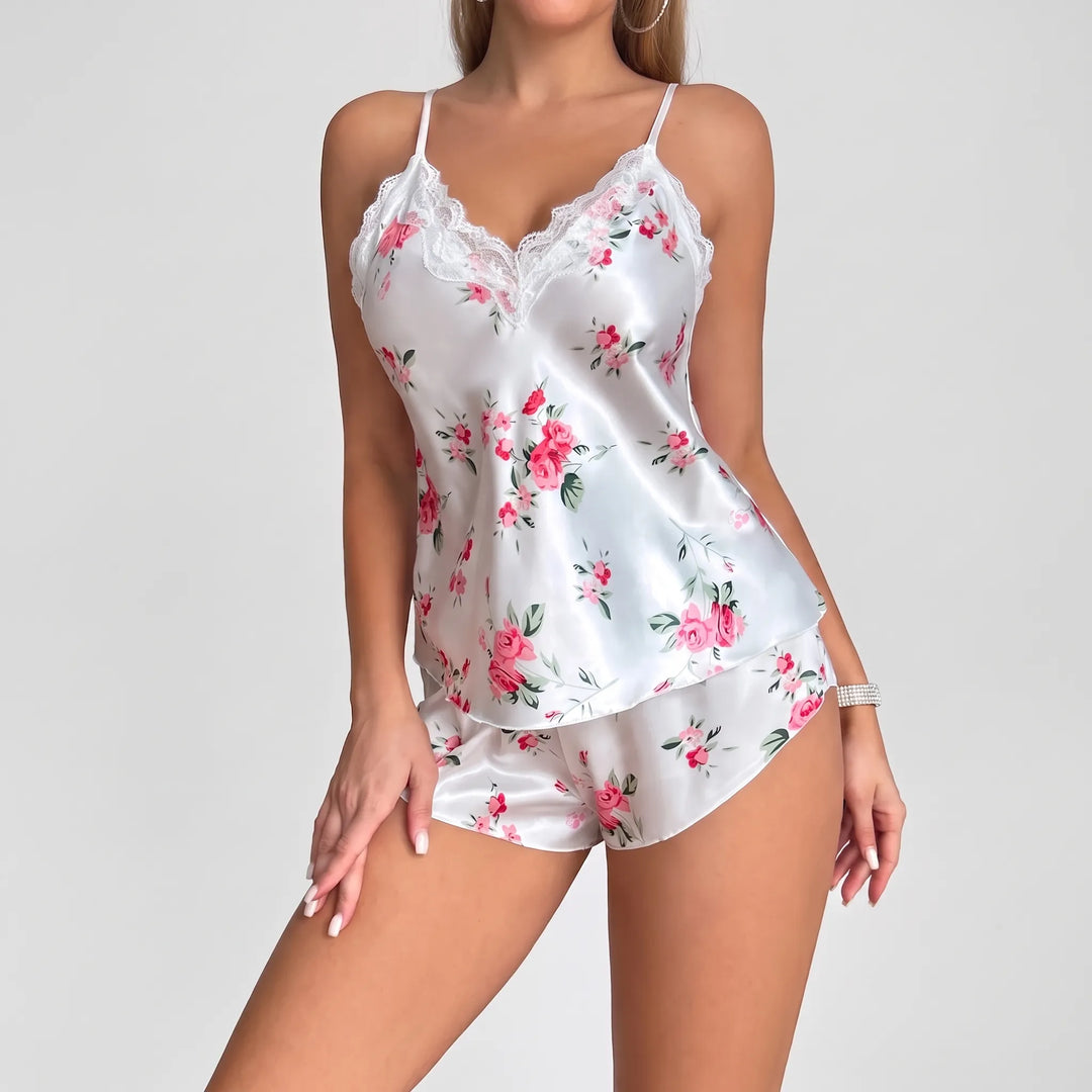 Model posing in the white satin set, three-quarter front view showing the lace-trimmed V-neck cami and rose-print shorts. 2
