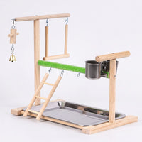 Wooden bird playstand on a plain background, seen from the front left, with ladder, swing, bell, green perch, steel cups and tray. 1