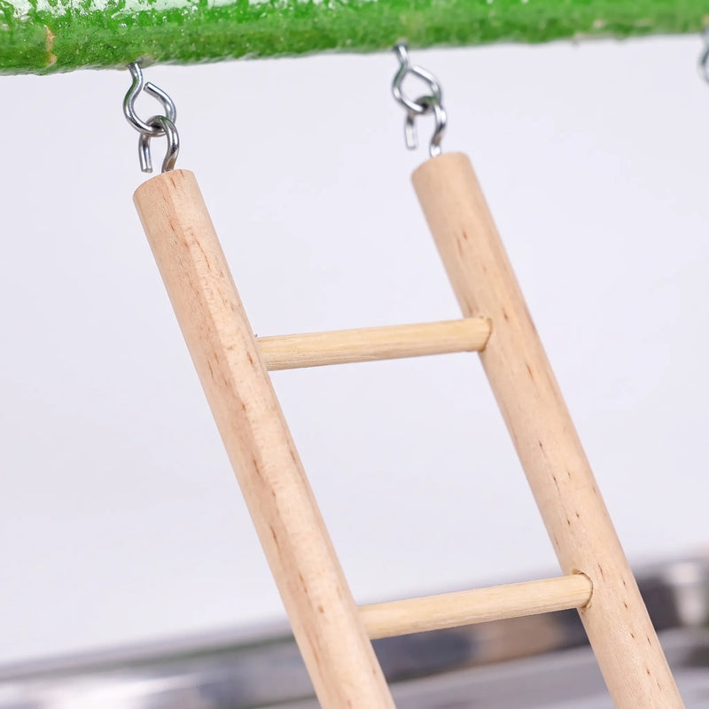 Close-up of the wooden ladder hanging from the green perch by metal screw hooks, with the steel tray blurred below. 3