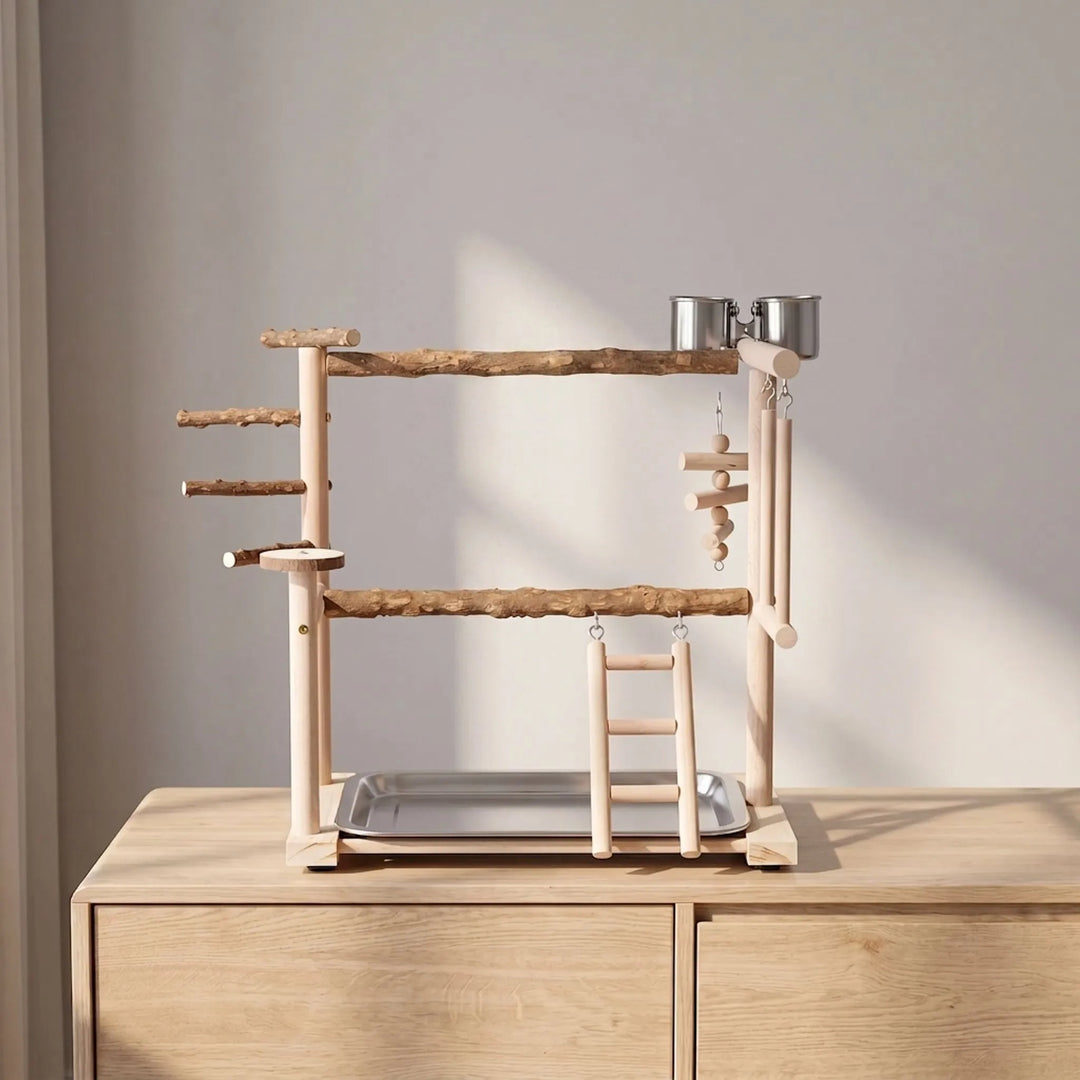 Wooden bird play stand on a pale wooden sideboard in soft daylight, seen from the front with perches, ladder and cups. 3