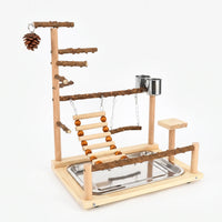 Wooden bird play stand on a plain white background, with natural branch perches, rope-bead ladder, swing, steel cups, pine cone and tray. 1