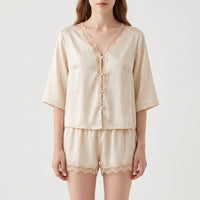 Front view on a model of the cream satin button-up top and shorts, with lace on the V-neckline and hems. 2