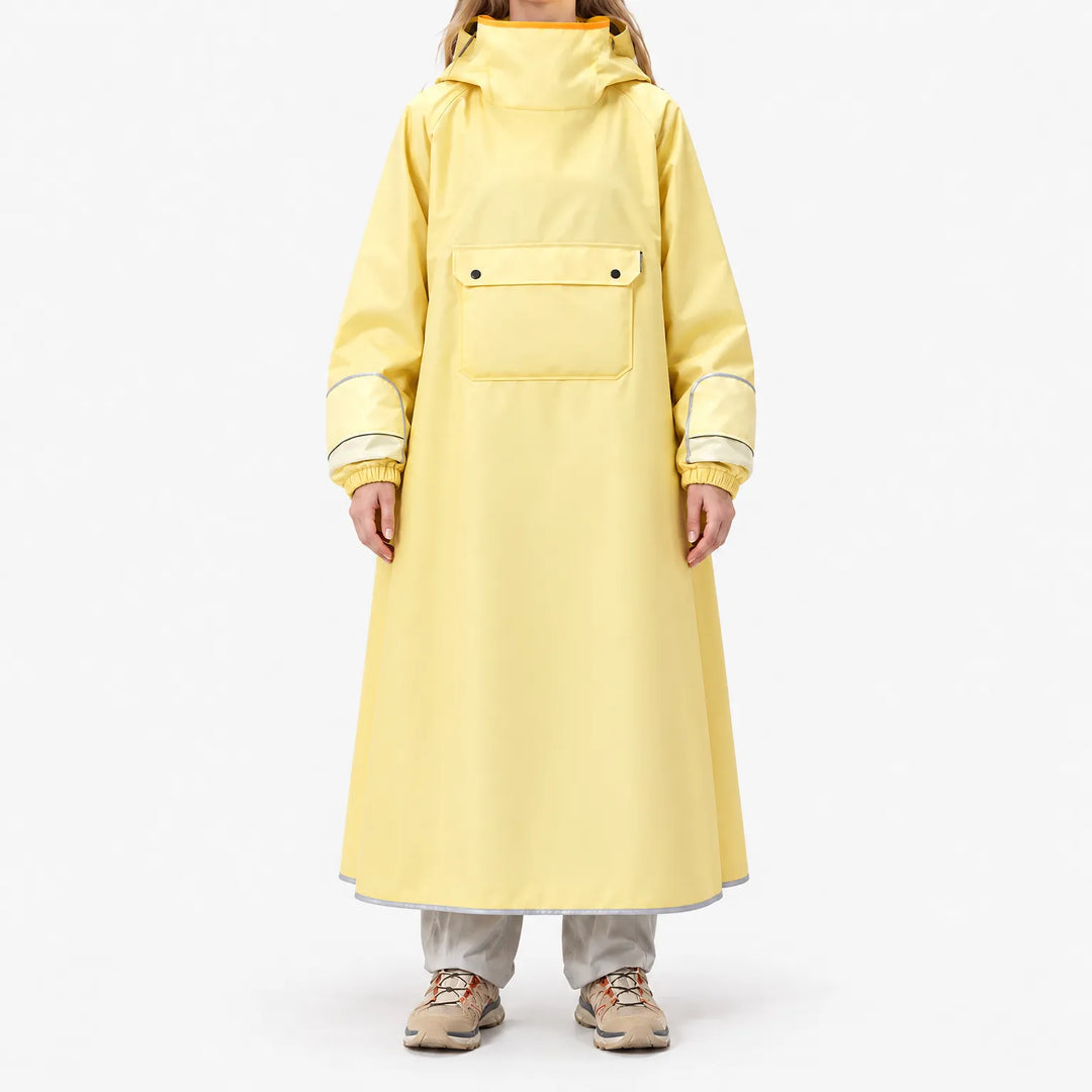 Front view of a model standing in the long yellow poncho, showing the large chest flap pocket, elasticated cuffs and reflective hem trim. 2
