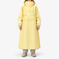 Front view of a model standing in the long yellow poncho, showing the large chest flap pocket, elasticated cuffs and reflective hem trim. 2
