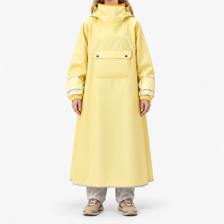 Front view of a model standing in the long yellow poncho, showing the large chest flap pocket, elasticated cuffs and reflective hem trim. 2