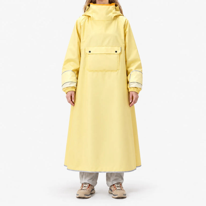 Front view of a model standing in the long yellow poncho, showing the large chest flap pocket, elasticated cuffs and reflective hem trim. 2