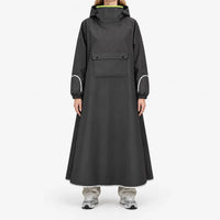Front view of a model in the black version of the long poncho, with chest flap pocket, reflective sleeve and hem trim, and neon lime collar lining. 4