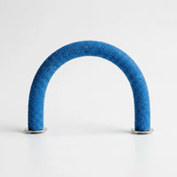 Blue gritty-textured curved perch standing upright in an arch on two metal washers against a plain white background. 1