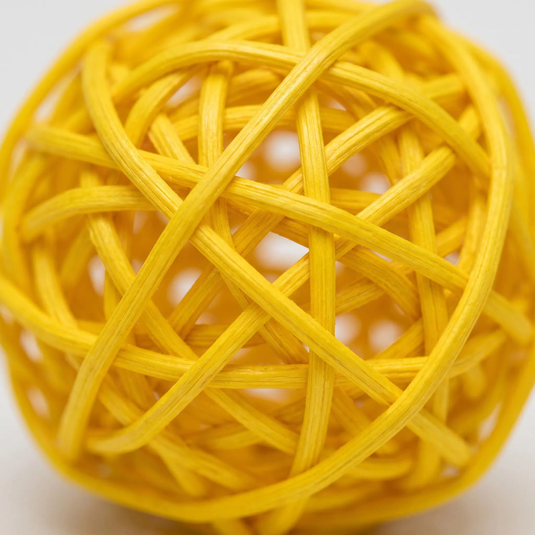 Close-up of a yellow woven ball showing its tightly interlaced, slightly ridged strands and the open gaps between them. 4