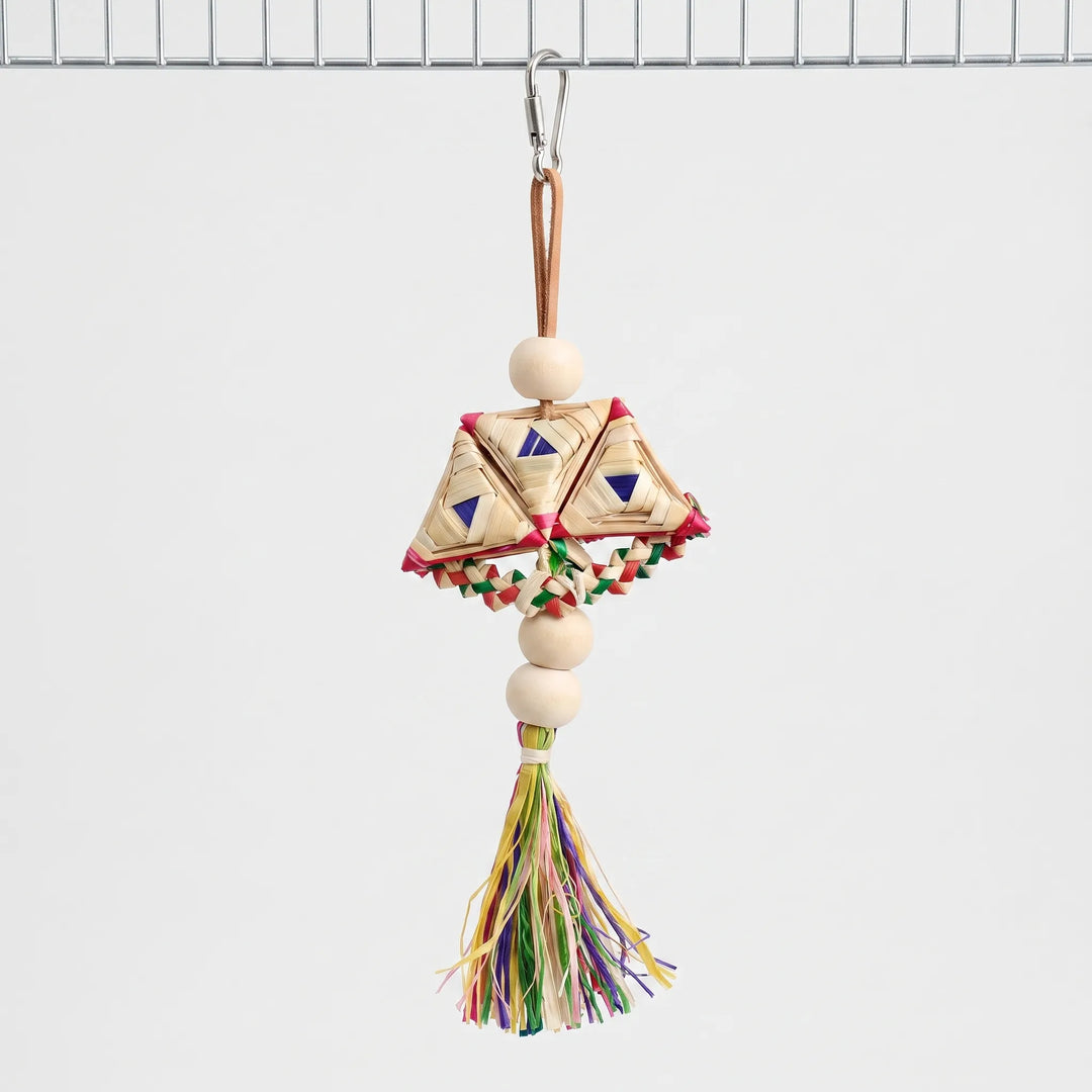 Whole woven toy hanging from a steel clip on a cage wire, with wooden beads, braided straw triangles and a colourful tassel. 1