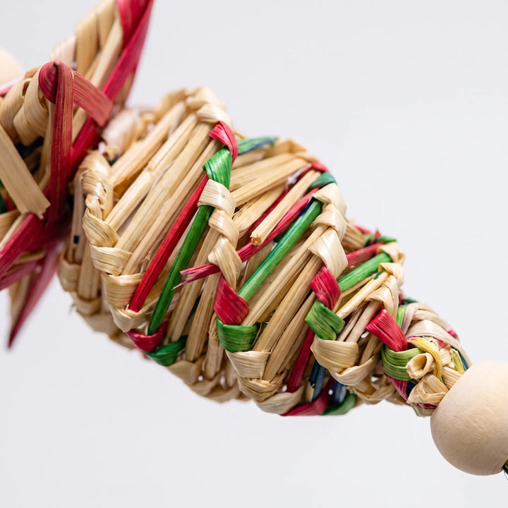Close-up of the braided straw weave in red, green and natural tones, next to a smooth wooden bead. 3