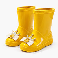 Pair of bright yellow rain boots angled to show the crown, bow and gem toe decoration, textured soles and tan fabric lining. 10