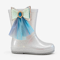 Side view of a single silver glitter boot with a large jewelled mint bow and layered blue tulle trailing down the shaft. 4
