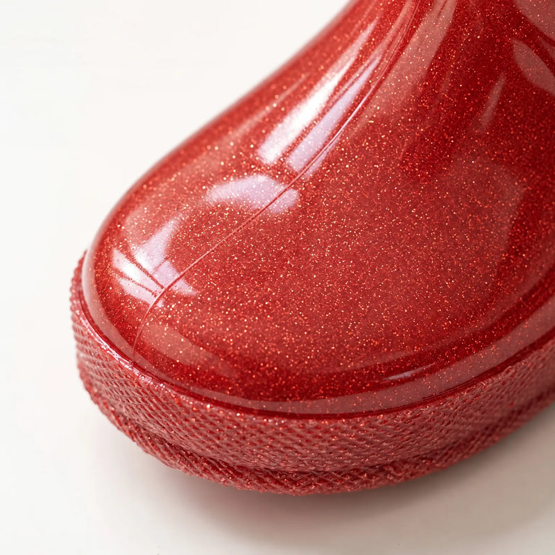 Close-up of the toe of a red glitter rain boot showing the sparkling glossy surface and textured sole edge. 6