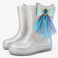 Pair of silver glitter boots at an angle, one with a jewelled mint bow and blue tulle streamers on the side. 7