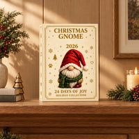 Cream and gold gnome advent box standing on a wooden mantel, styled with evergreen sprigs, red berries, a lit candle and small books. 1