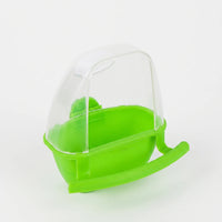 Green plastic feeder with a clear hood and a curved perch, shown at an angle on a plain light background. 1