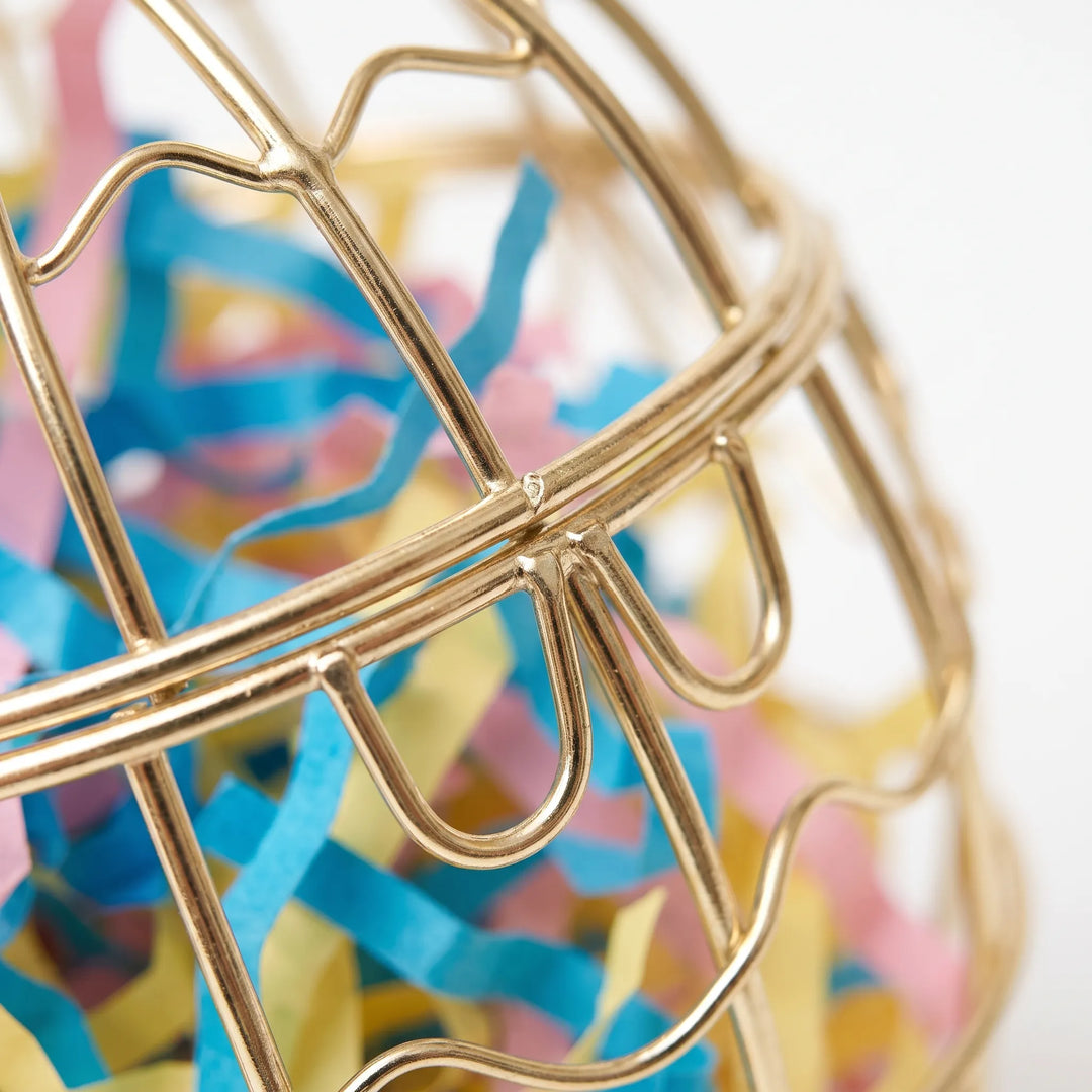 Close-up of the gold wire bars and latch loops, with blue, pink and yellow shredded paper visible inside. 3