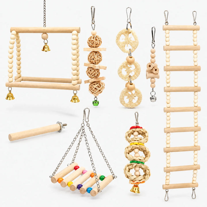 Set of wooden bird toys laid out on white: bead swings, ladder, rattan balls, loofah slices, straw rings, perch and bells. 1