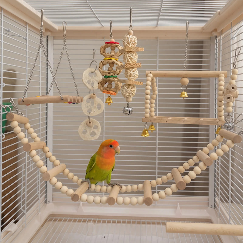 Colourful lovebird perched on a curved bead-and-wood bridge inside a cage, with the other hanging toys and bells around it. 2