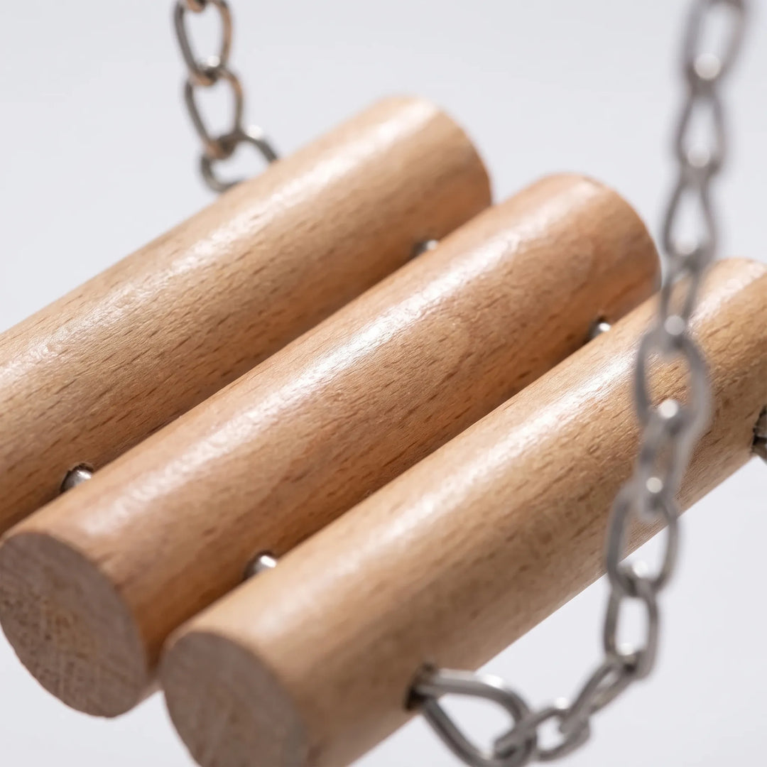 Close-up of three smooth wooden dowels joined by metal fixings, with chain links hanging either side. 3