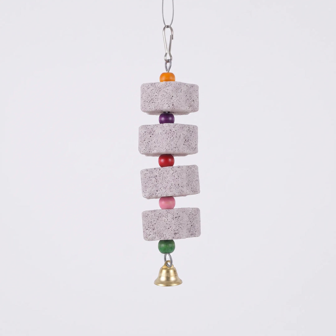 Four porous grey stone blocks strung with orange, purple, red, pink and green wooden beads, a clip above and a brass bell below, on plain background. 1
