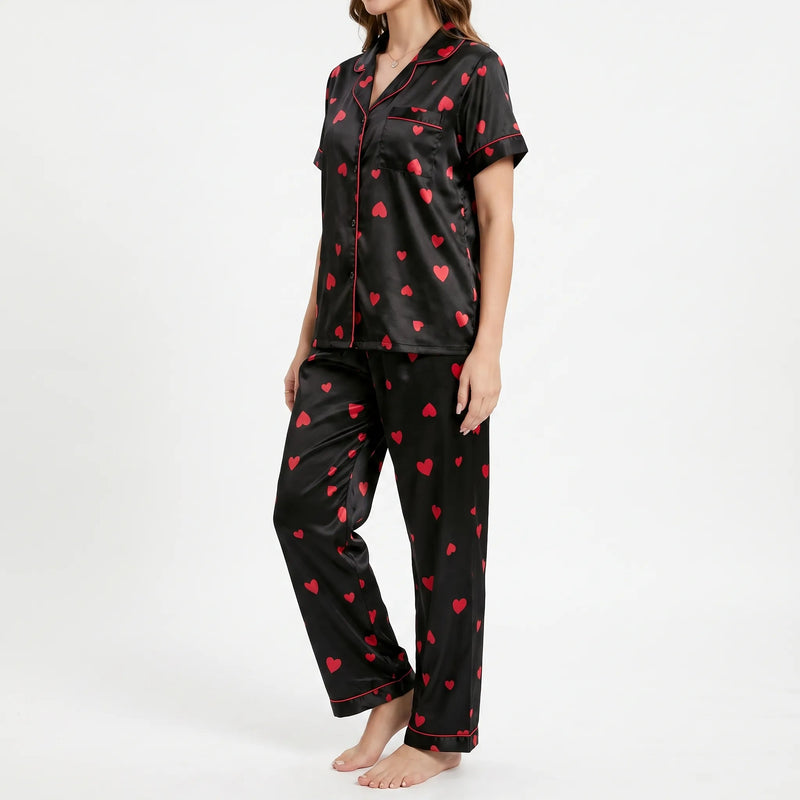 Three-quarter side view of a model in the black satin pyjamas, showing the red piping, chest pocket and buttoned front. 4