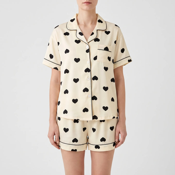 Model wearing the short-sleeve version of the heart print pyjamas with matching shorts, front view with button placket. 5