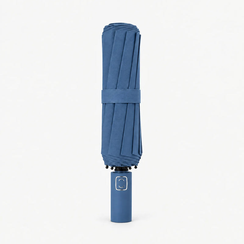 Folded denim blue umbrella standing upright on a white background, canopy secured by a fabric strap. 11